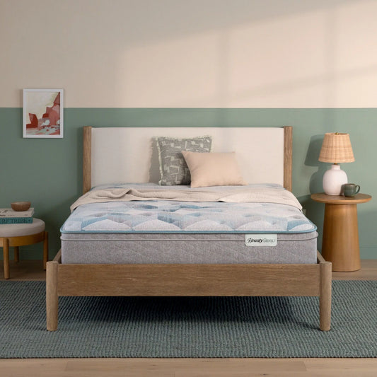 Beautysleep by Beautyrest mattress in a brown bedframe in a room setting with a lamp and nightstand.