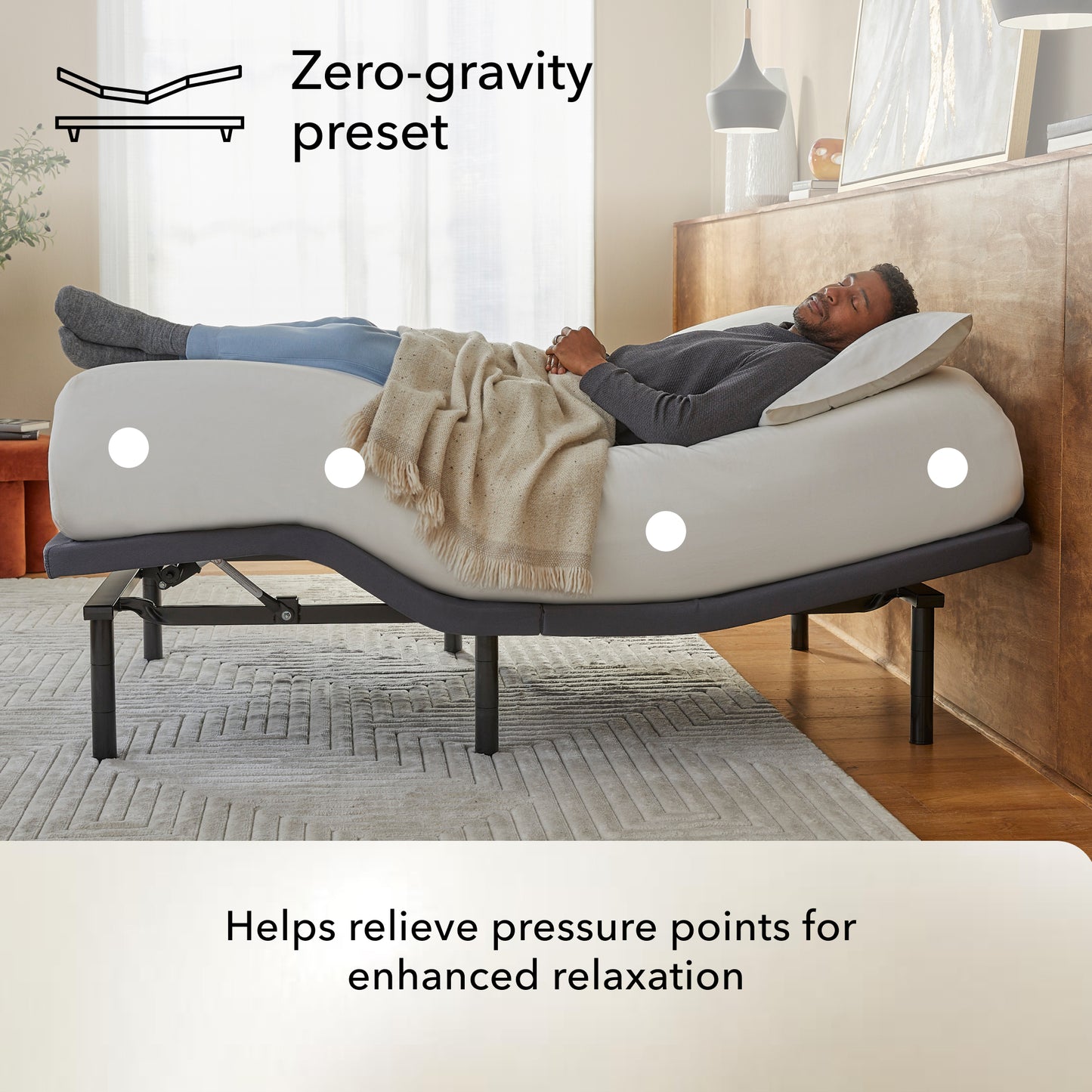 Man lying on a bed on top of a Baselogic Pearl adjustable base with 'Zero-gravity preset' feature in a bedroom setting.