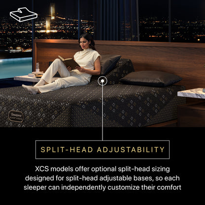 Woman reading a book on a Beautyrest Black Hybid XCS medium  split-head adjustable bed with a cityscape view.