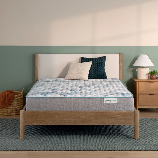Beautysleep by Beautyrest mattress in a brown bedframe in a room setting with a lamp and nightstand.